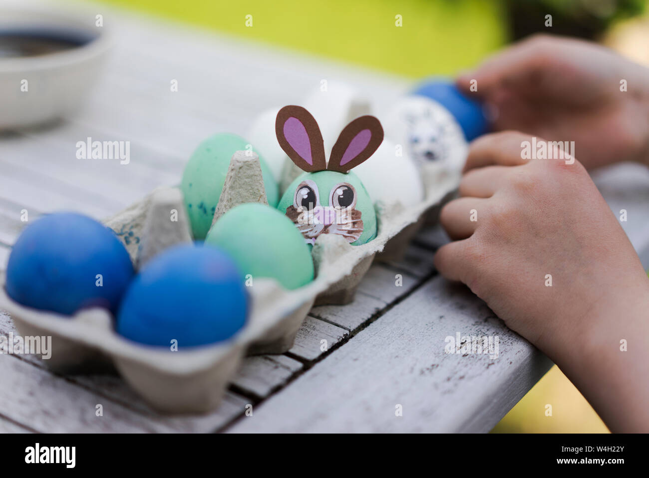 Close-up di ragazza decorazione di uovo di pasqua sul tavolo da giardino Foto Stock