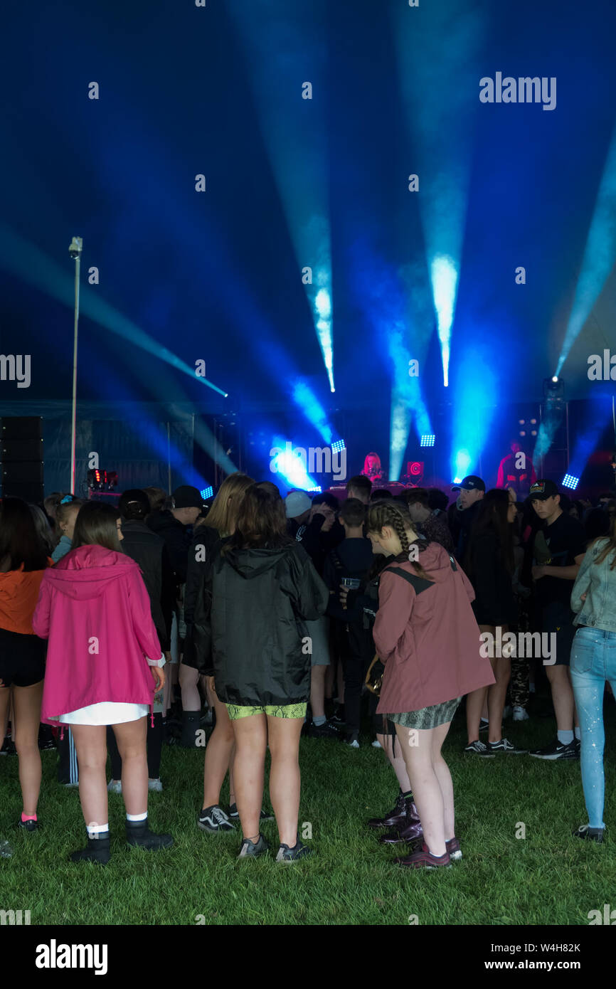 Gli adolescenti ascoltando musica rave in una grande marca in un outdoor festival di musica Foto Stock