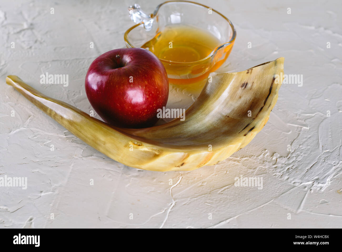 Rosh ha-shana Jewish nuovo anno composizione di una mela rossa, un vasetto di miele e Shofar avvisatore acustico per Rosh Hashanah. Foto Stock