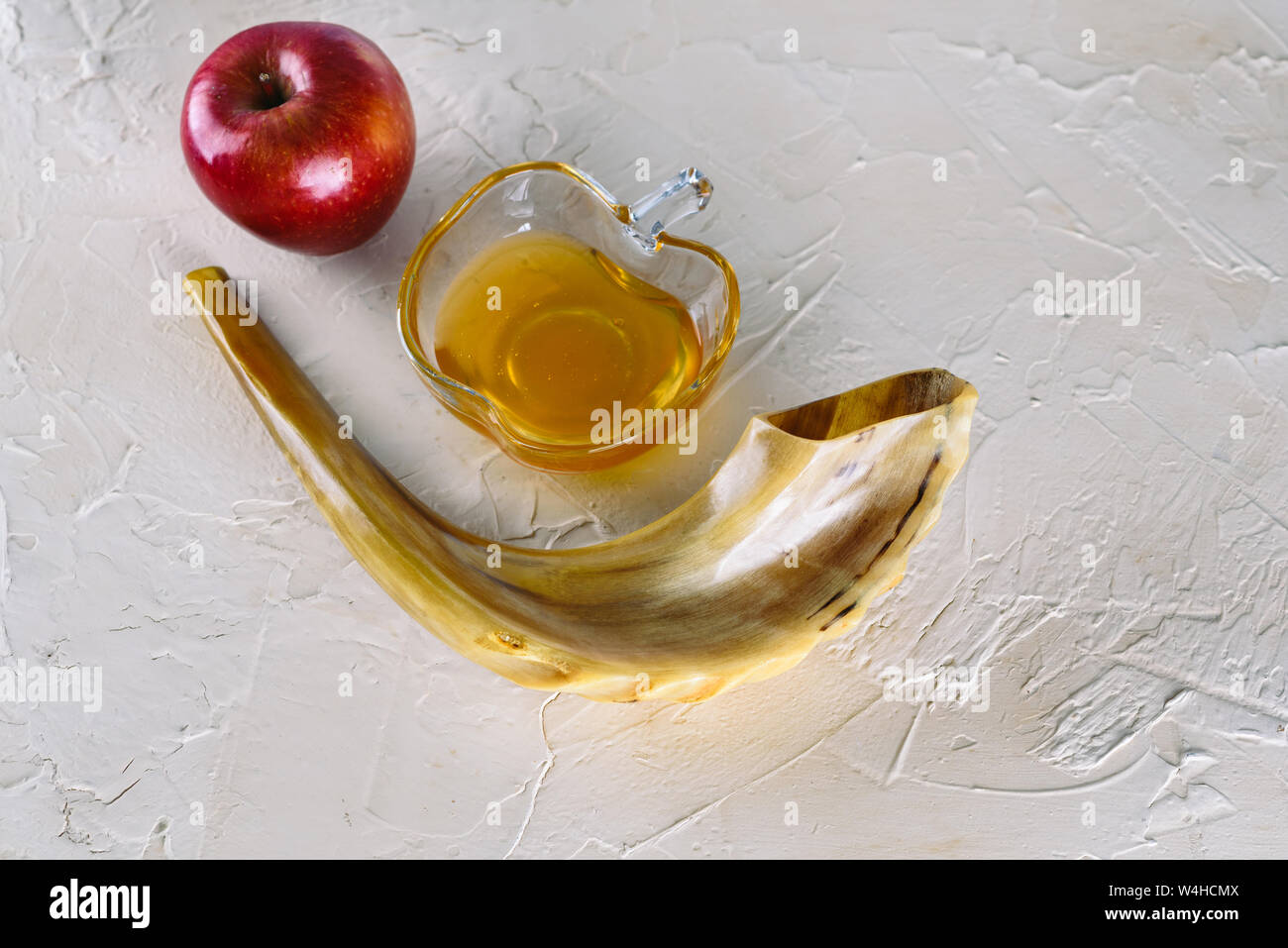 Rosh ha-shana Jewish nuovo anno composizione di una mela rossa, un vasetto di miele e Shofar avvisatore acustico per Rosh Hashanah. Foto Stock