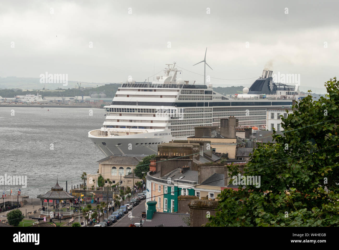 Con vista su Cobh della nave da crociera MSC Orchestra domina la vista mentre attracca al terminal delle navi da crociera di Cobh, County Cork, Irlanda. Foto Stock