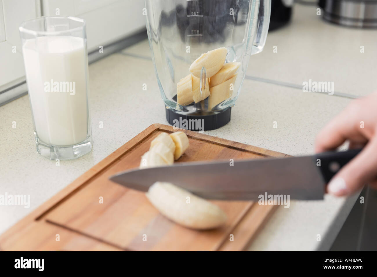 Un giovane uomo si prepara un frullato di latte e frutta fresca per la colazione. Egli conduce uno stile di vita sano. Foto Stock