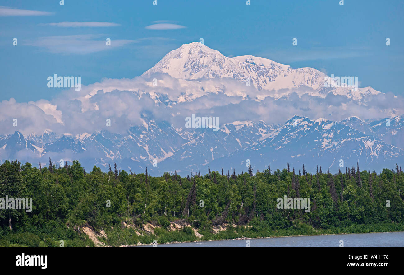Vista ingrandita del picco di Denali in Alaska Range con una foresta e il lago in primo piano il cielo blu e nuvole di piccole dimensioni in background Foto Stock