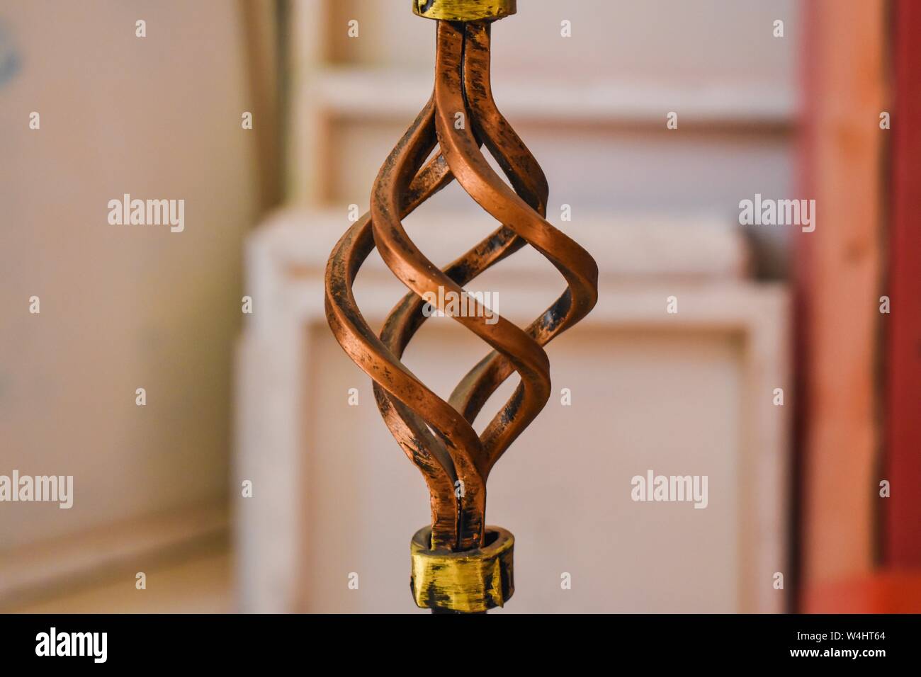 Primo piano della spirale decorativa in metallo, con tele e oggetti d'arte sullo sfondo. Foto Stock