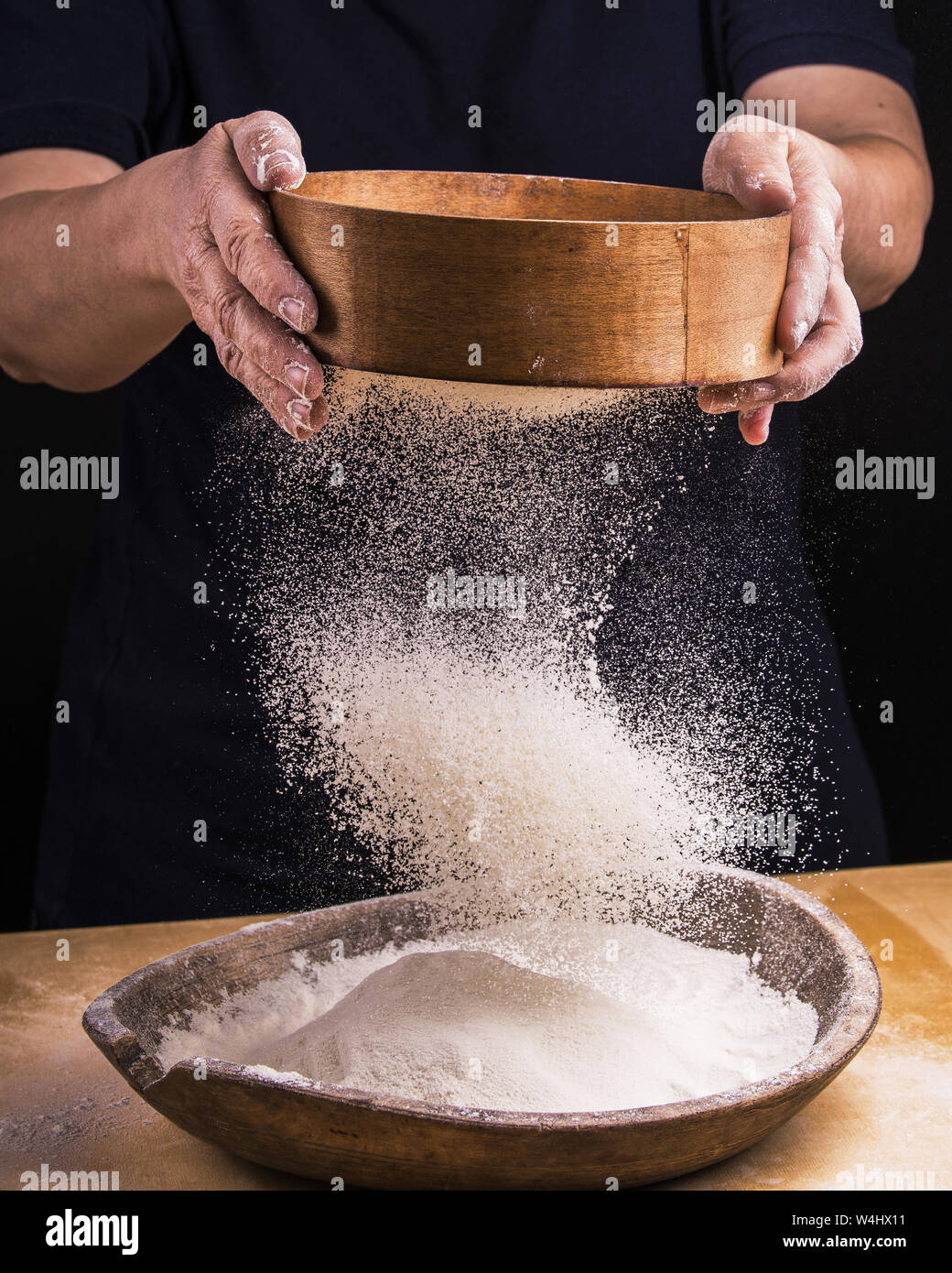 Primo piano delle mani di una donna che gioca a setacciare la farina per la preparazione di pasta Foto Stock