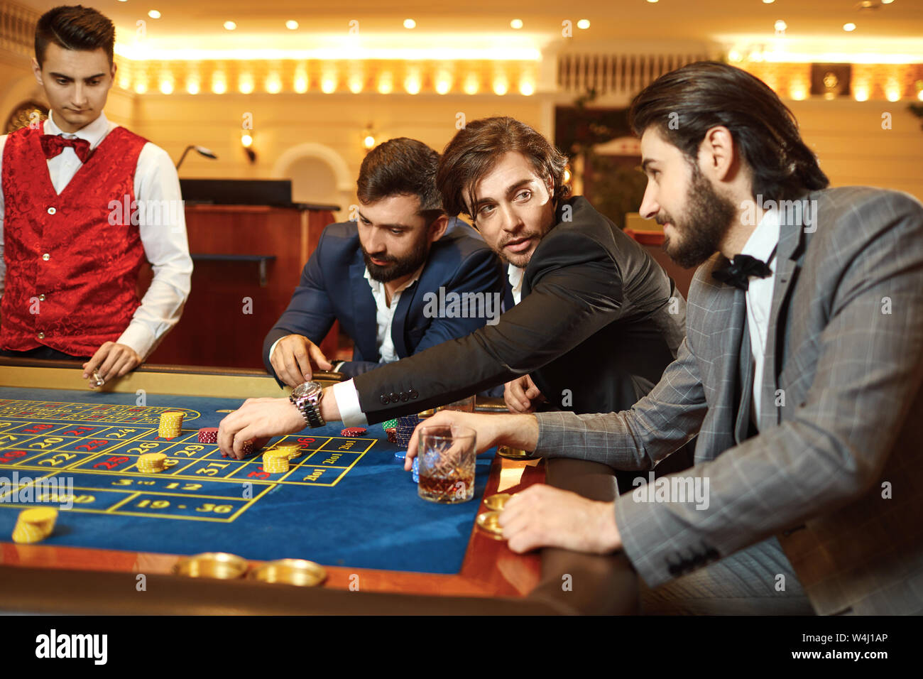Gruppo uomo giocatore in un vestito al tavolo della roulette giocando a poker in un casinò. Foto Stock