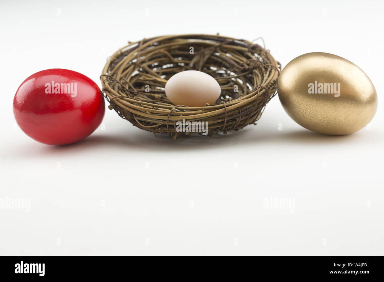 Investire i simboli di rosso, oro e piccolo nido uova riflettono start finanziari, i rischi e le opportunità di successo. Su sfondo bianco con copia spazio. Foto Stock