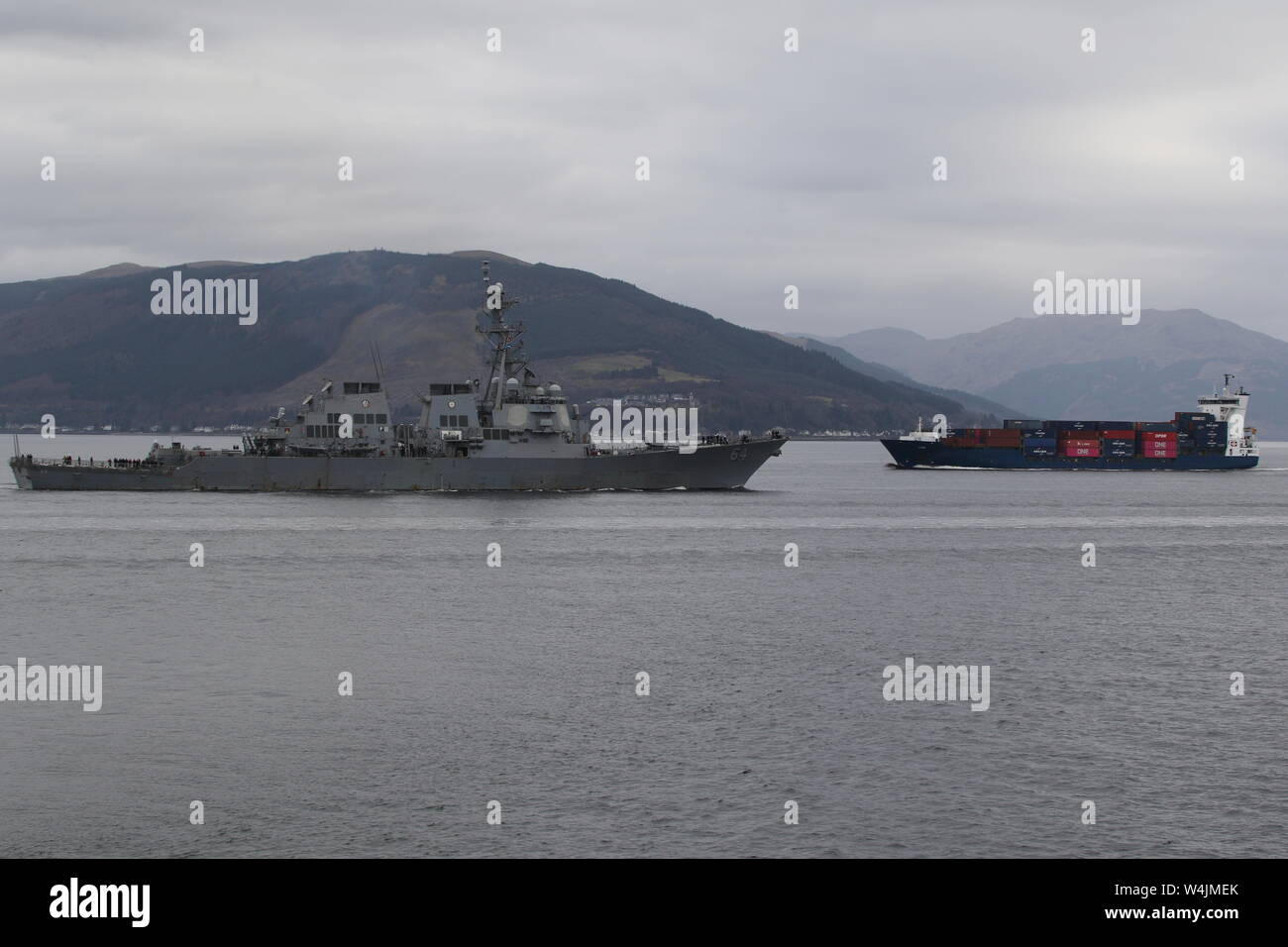 USS Carney (DDG-64) è visto qui in entrata per Faslane durante l'esercizio comune della Warrior 19-1, come la nave portacontainer LIsa testa fuori da Greenock. Foto Stock