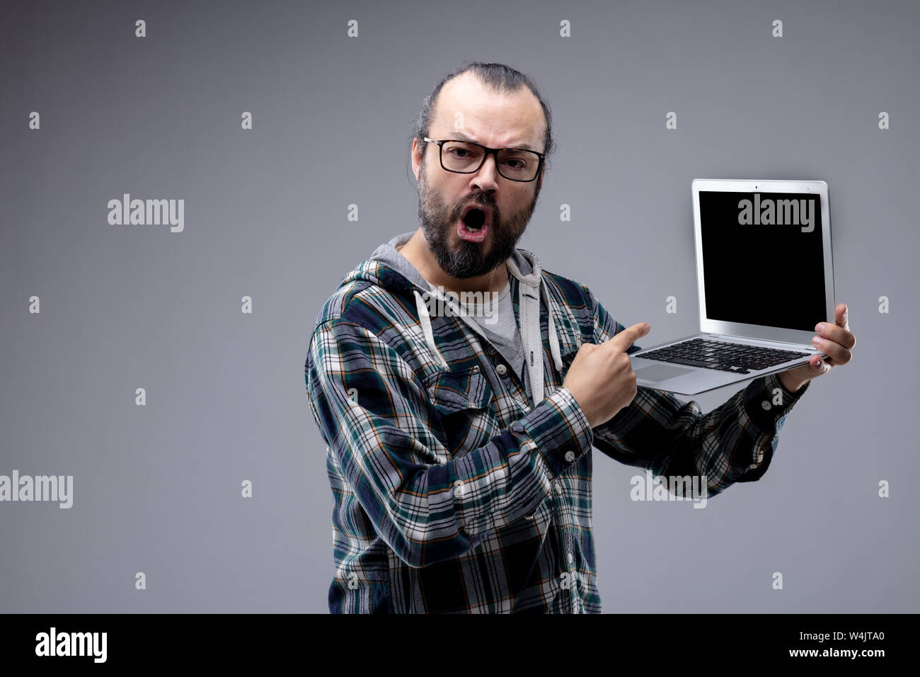 Polemico arrabbiati uomo puntando il suo laptop come egli parla alla telecamera con la bocca aperta cercando di fare un punto e presentare una prova o di spiegare il suo argum Foto Stock