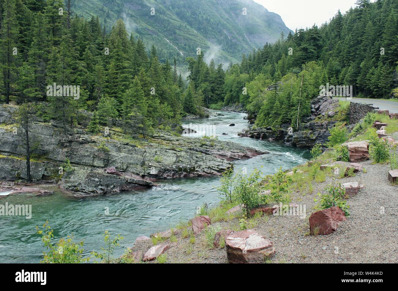 Lago curvo che scorre in mezzo a scogliere rocciose e colline con alberi e una montagna boscosa Foto Stock