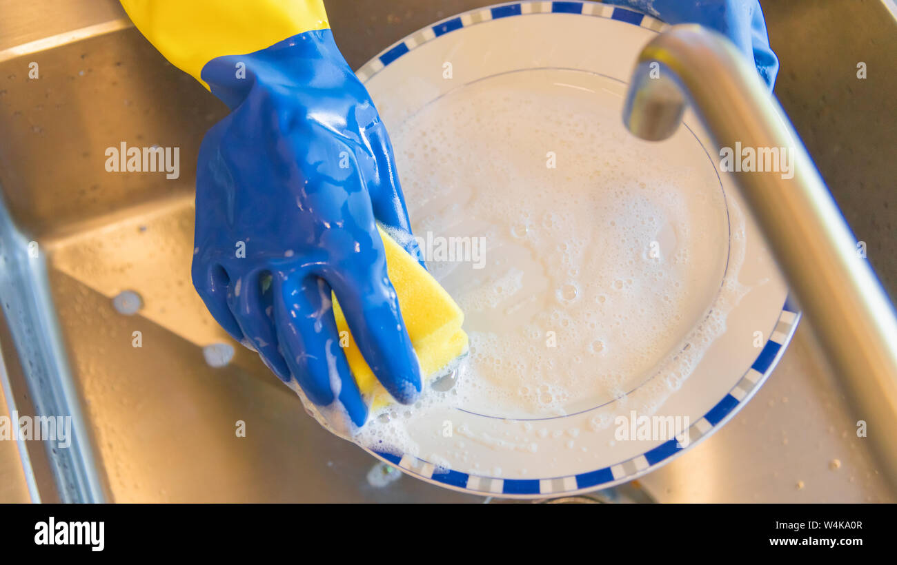 Lavare i piatti in cucina - giallo e blu - guanti di plastica con un sacco  di schiuma - Maschio lavando i piatti in cucina zona lavandino - vista  superiore Foto stock - Alamy