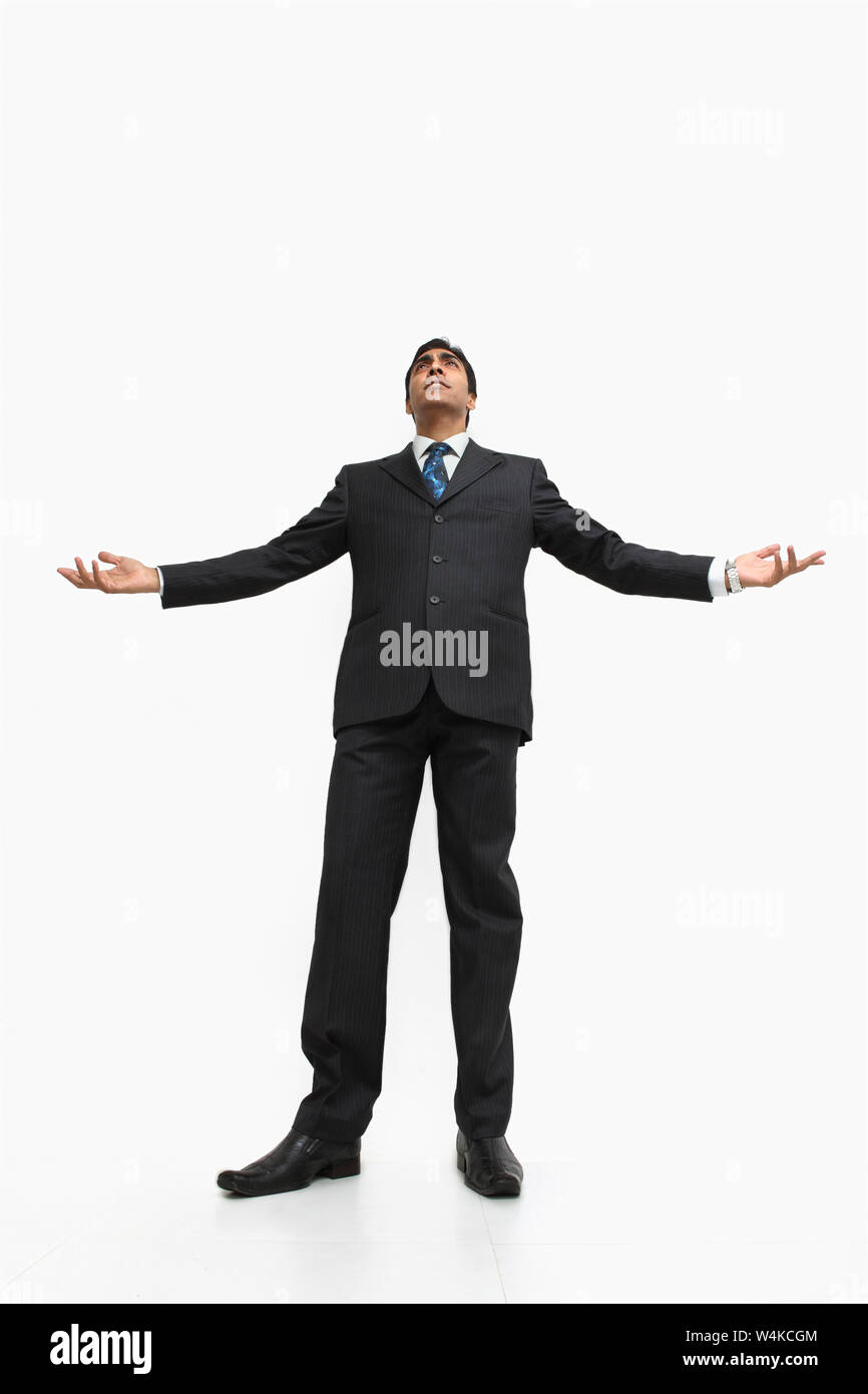 Basso angolo di visione di un commerciante indiano in piedi con le braccia tese Foto Stock