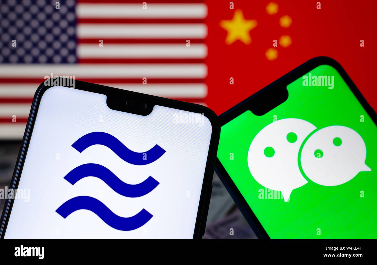 Facebook Libra e loghi WeChat sullo smartphone e sfocato bandiere degli Stati Uniti e della Cina sullo sfondo. Foto concettuale. Foto Stock