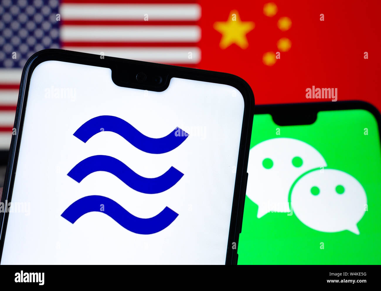 Facebook Libra e loghi WeChat sullo smartphone e sfocato bandiere degli Stati Uniti e della Cina sullo sfondo. Foto concettuale. Foto Stock