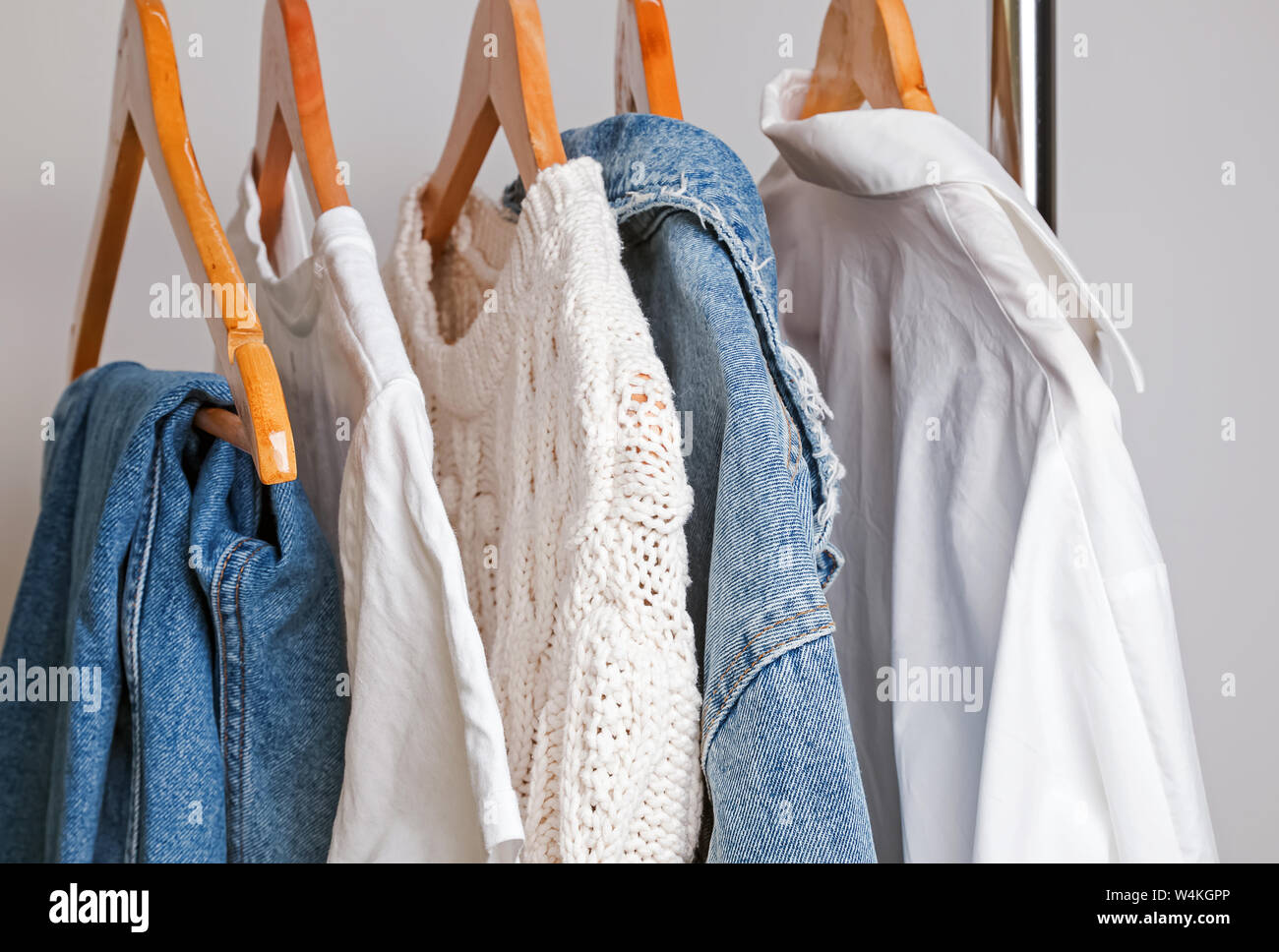 Donna guardaroba minimalista in bianco e denim su appendiabiti close-up Foto Stock