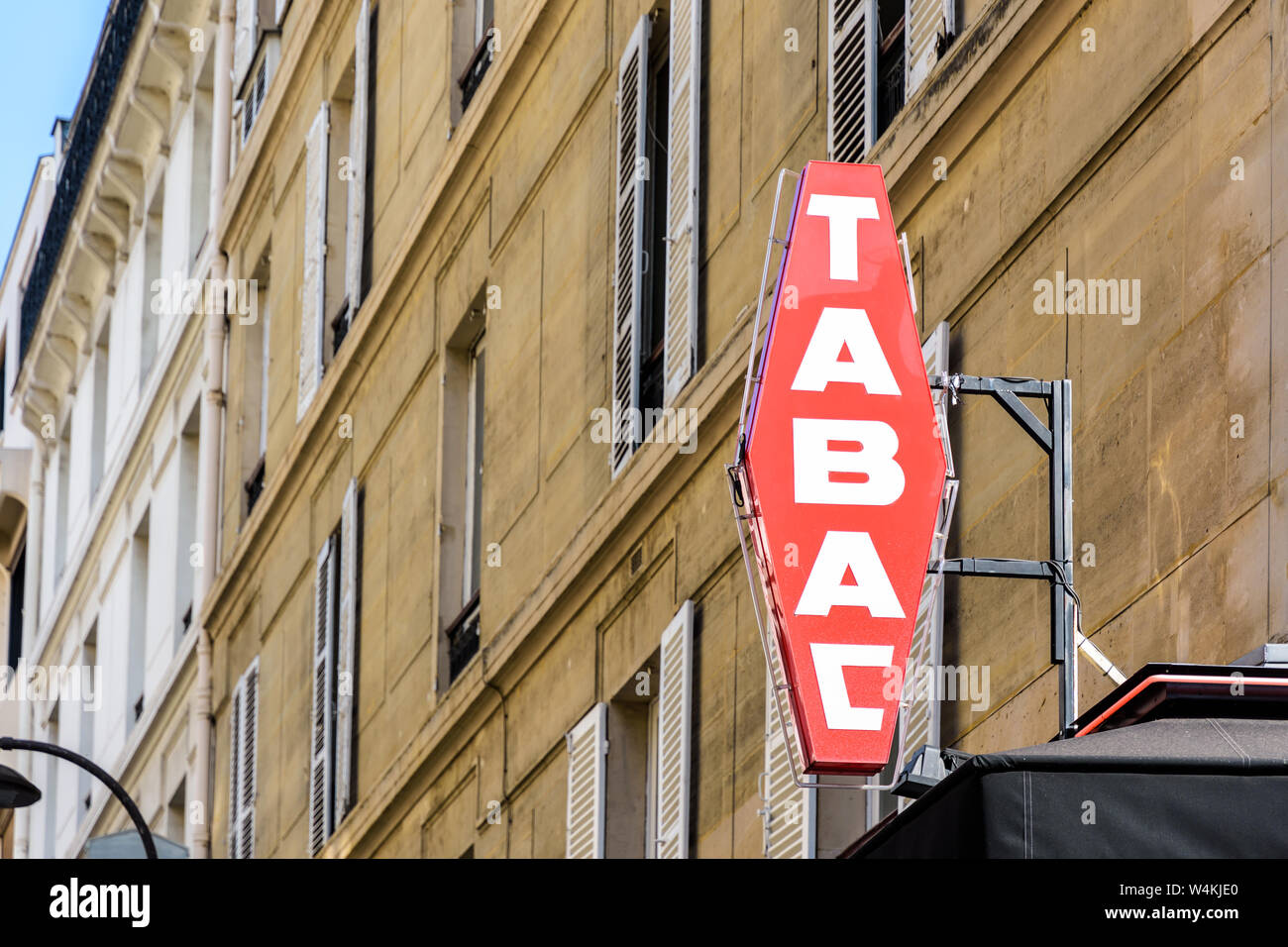 Rosso francese il tabacco shop segno bianco con scritte e un edificio in background. Foto Stock