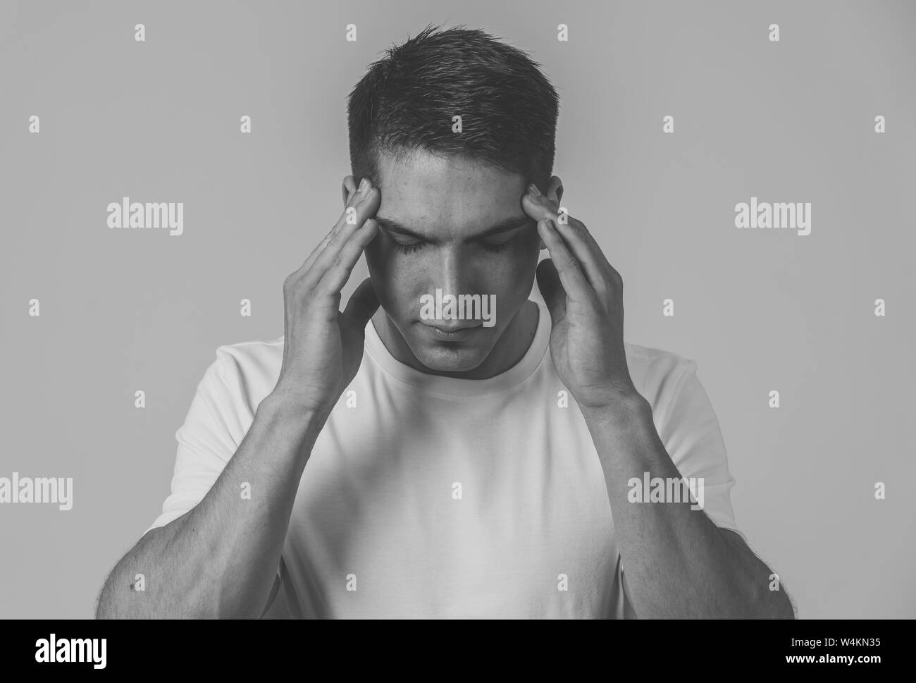Close up ritratto del bel giovane latina gara misti uomo con mal di testa che soffre di emicrania, le mani sulle tempie gli occhi chiusi che mostra un forte dolore. Med Foto Stock