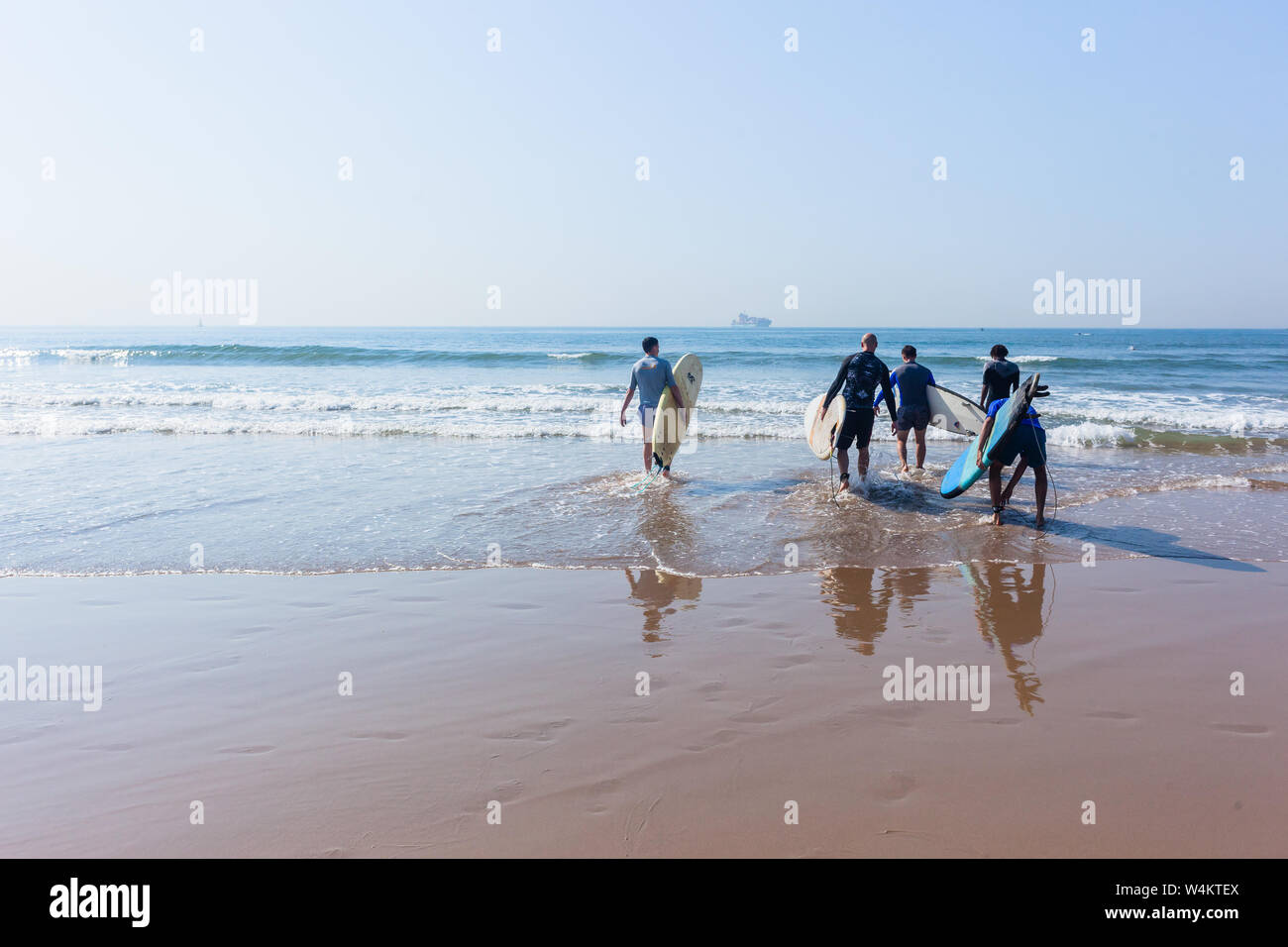 Lezioni di surf sulla spiaggia con tavole da surf con giovani uomini e istruttori di surf sulla base di wave riding skill accanto all'acqua dell'oceano litorale. Foto Stock