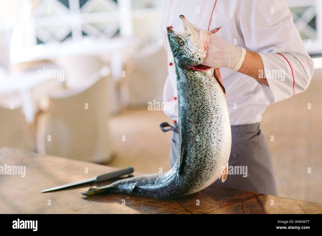 Lo Chef mantenere il salmone. Lo chef taglia il salmone sul tavolo. Foto Stock