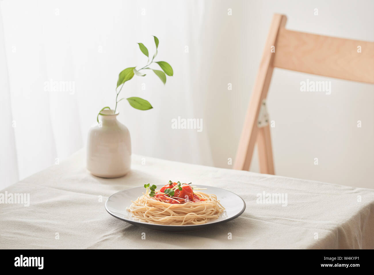La pasta fatta a mano con sugo di ragù sulla piastra su vintage white tavolo con scolapasta e fiori Foto Stock