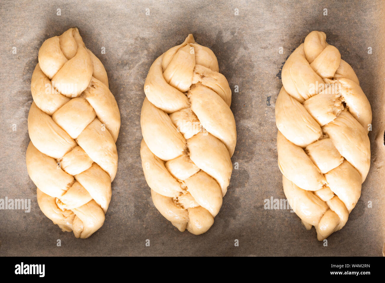 Cibo fatto in casa processo concetto calza a treccia di pane challah impasto su sfondo bianco con spazio di copia Foto Stock