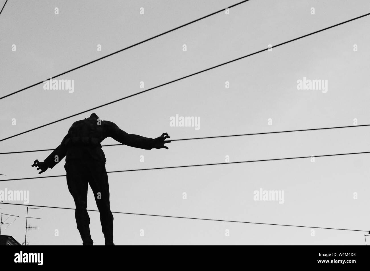 Primo piano di una silhouette di una persona nel aria con cavi che passano dietro il corpo Foto Stock