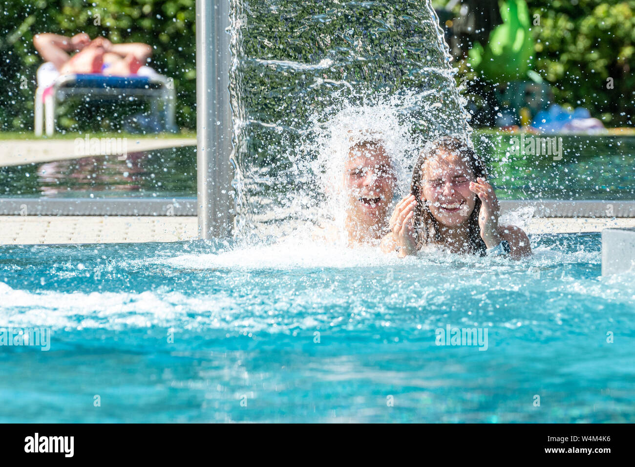 24 luglio 2019, il Land della Baviera, Passau: Lena e Jonas raffreddare sotto una cascata nella piscina all'aperto "peb'. La Germania si trova di fronte a un'ondata di calore - e già mercoledì questo sarà chiaramente evidente in molti settori. Foto: Armin Weigel/dpa Foto Stock