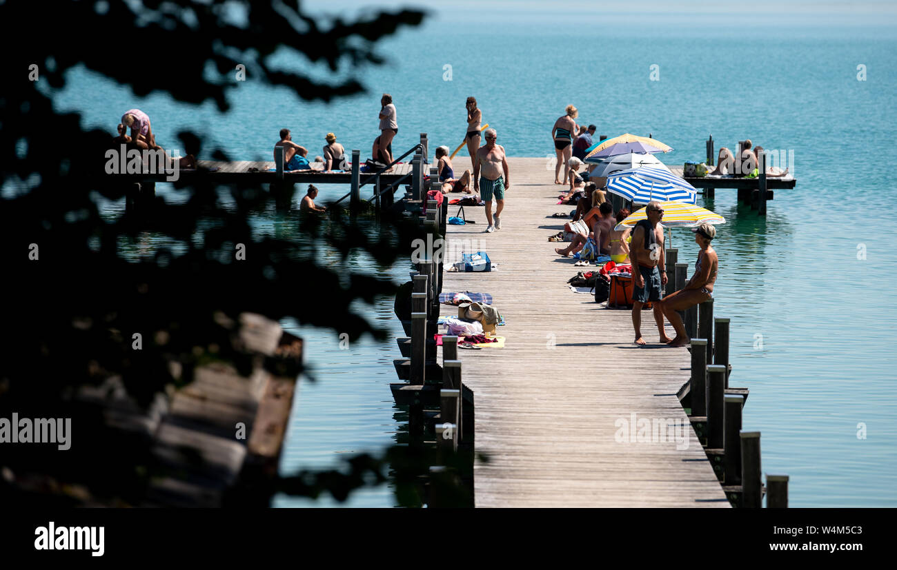 24 luglio 2019, il Land della Baviera, Inning: numerosi escursionisti di sedersi su un molo al worthsee nel sole e temperature elevate. Foto: Sven Hoppe/dpa Foto Stock