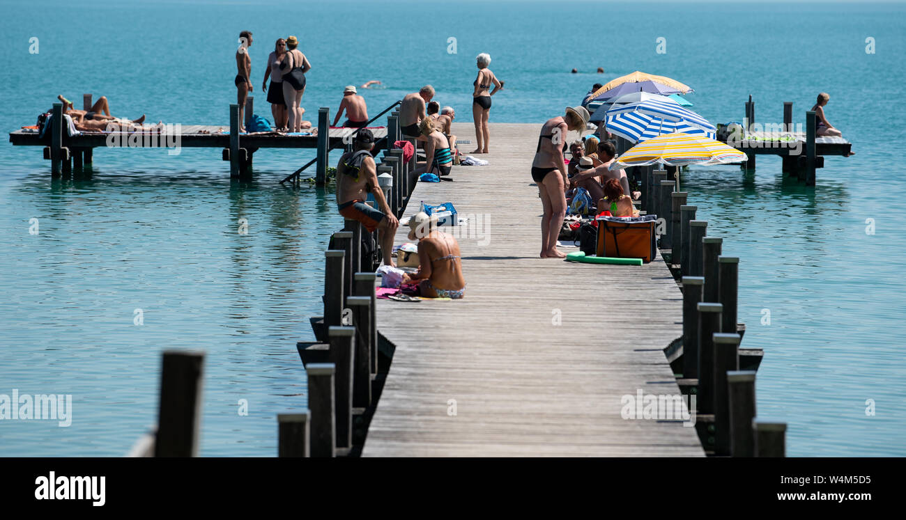 24 luglio 2019, il Land della Baviera, Inning: numerosi escursionisti di sedersi su un molo al worthsee nel sole e temperature elevate. Foto: Sven Hoppe/dpa Foto Stock