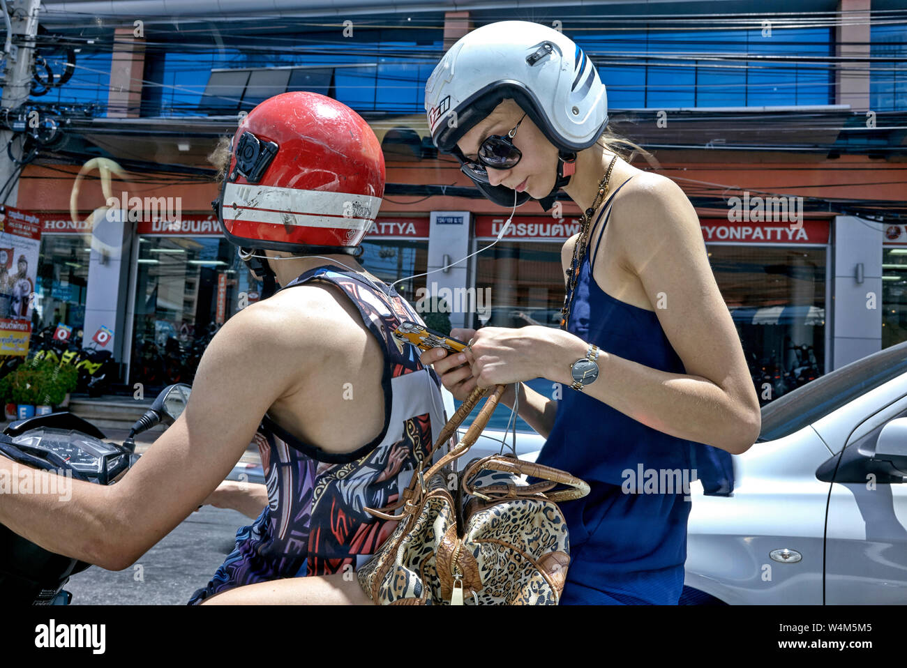 Donna moto. Cavalcare il pilone femminile su una moto e condividere la musica dal suo smartphone, tramite cuffie, con il pilota maschile. Foto Stock