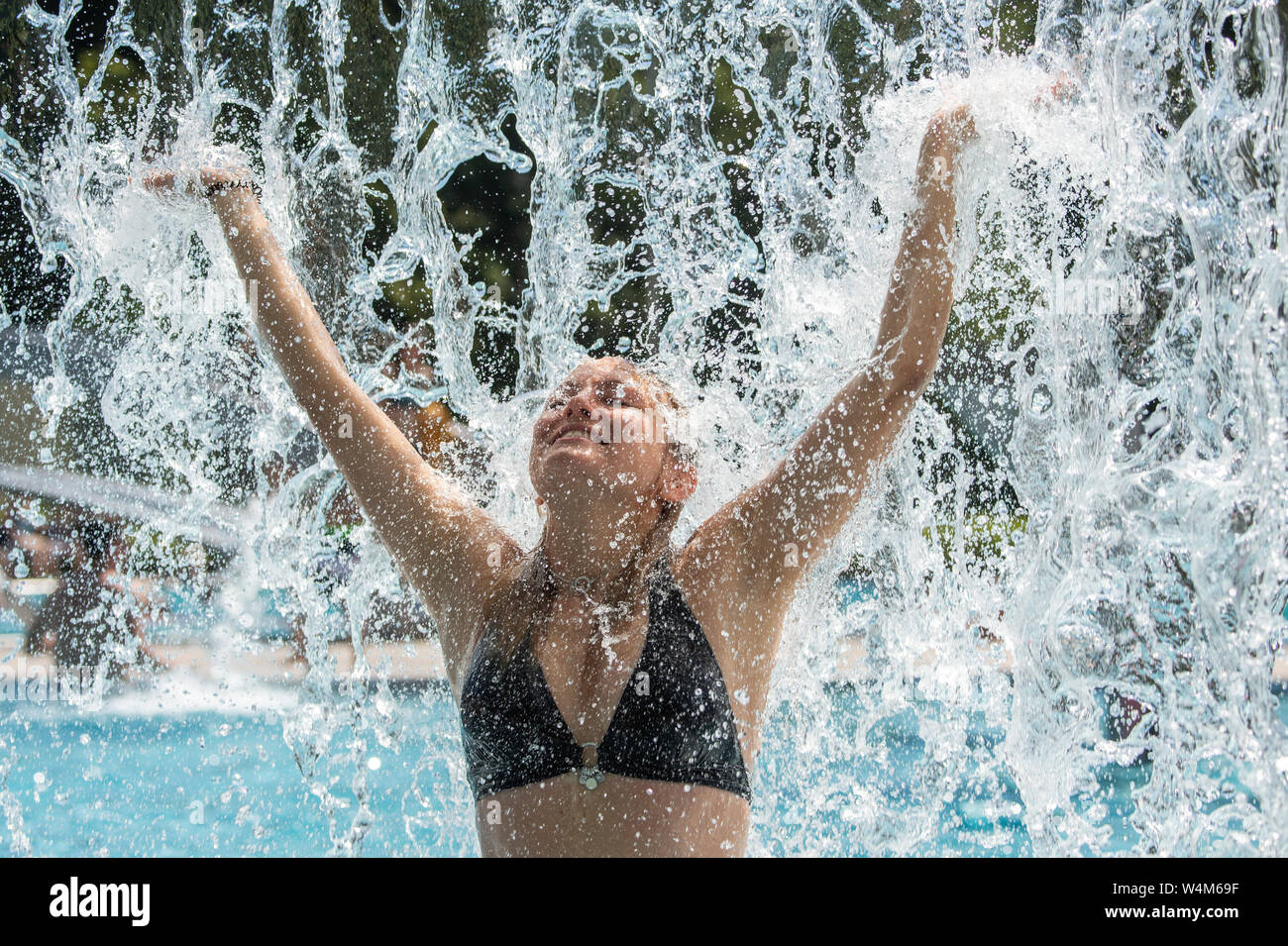 24 luglio 2019, in Sassonia, Großröhrsdorf: Antje da Dresda si erge su questo caldo giorno d'estate in Massenei-Bad nel distretto di Bautzen sotto una cascata artificiale e si raffredda. Foto: Robert Michael/dpa-Zentralbild/dpa Foto Stock