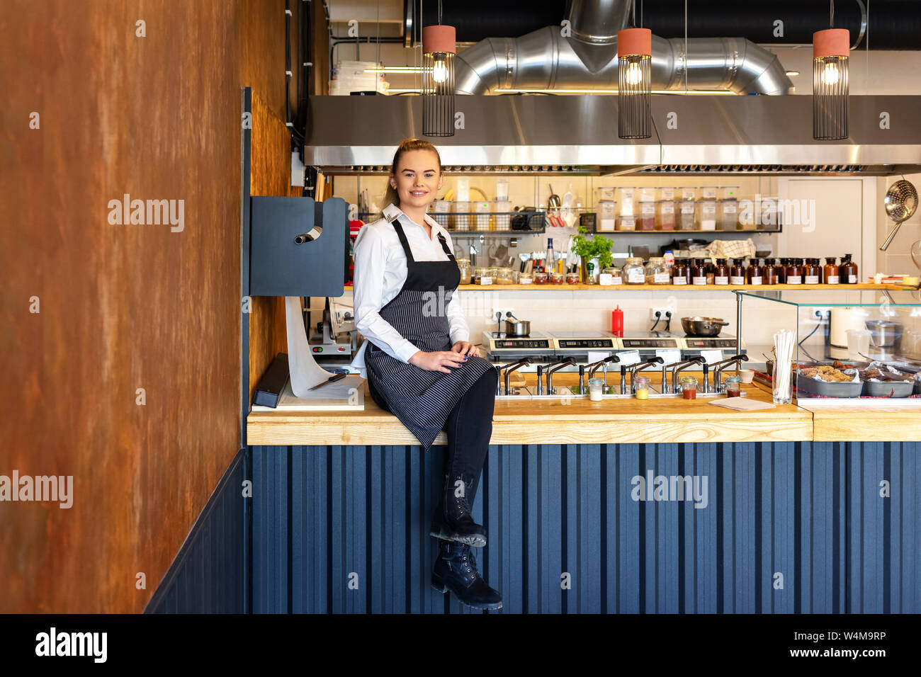 Felice successo della piccola proprietario del ristorante seduta sul contatore orgogliosa del suo small business Foto Stock