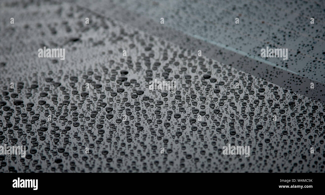 Le gocce di pioggia sulla superficie nera Foto Stock