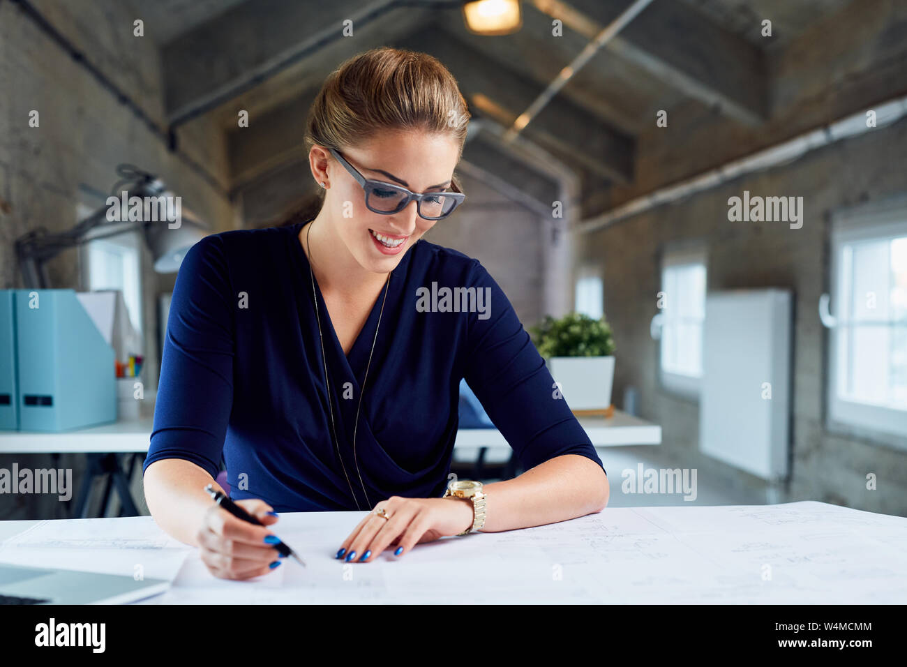 Bella imprenditrice lavora con progetti in ufficio industriale Foto Stock