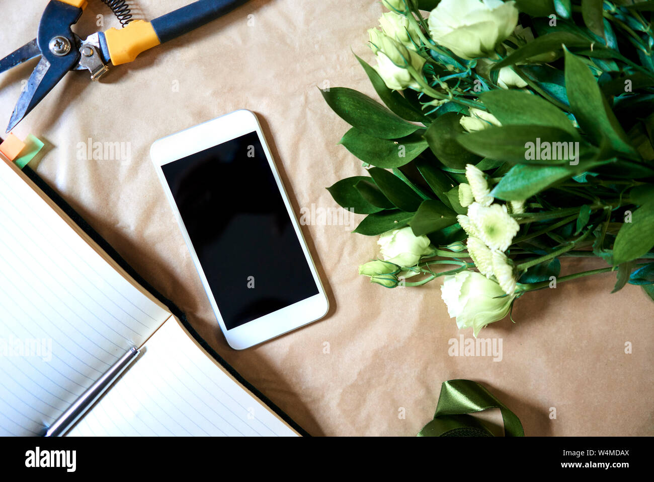 Mazzo di fiori e lo smartphone giacente sul contatore in un fioraio Foto Stock