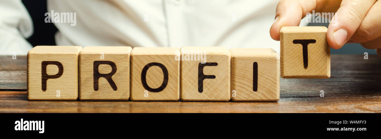 Imprenditore mette dei blocchi di legno con la parola profitto. Il risultato finanziario della società per un certo periodo di tempo. Reddito. Il ritorno sugli investimenti. P Foto Stock
