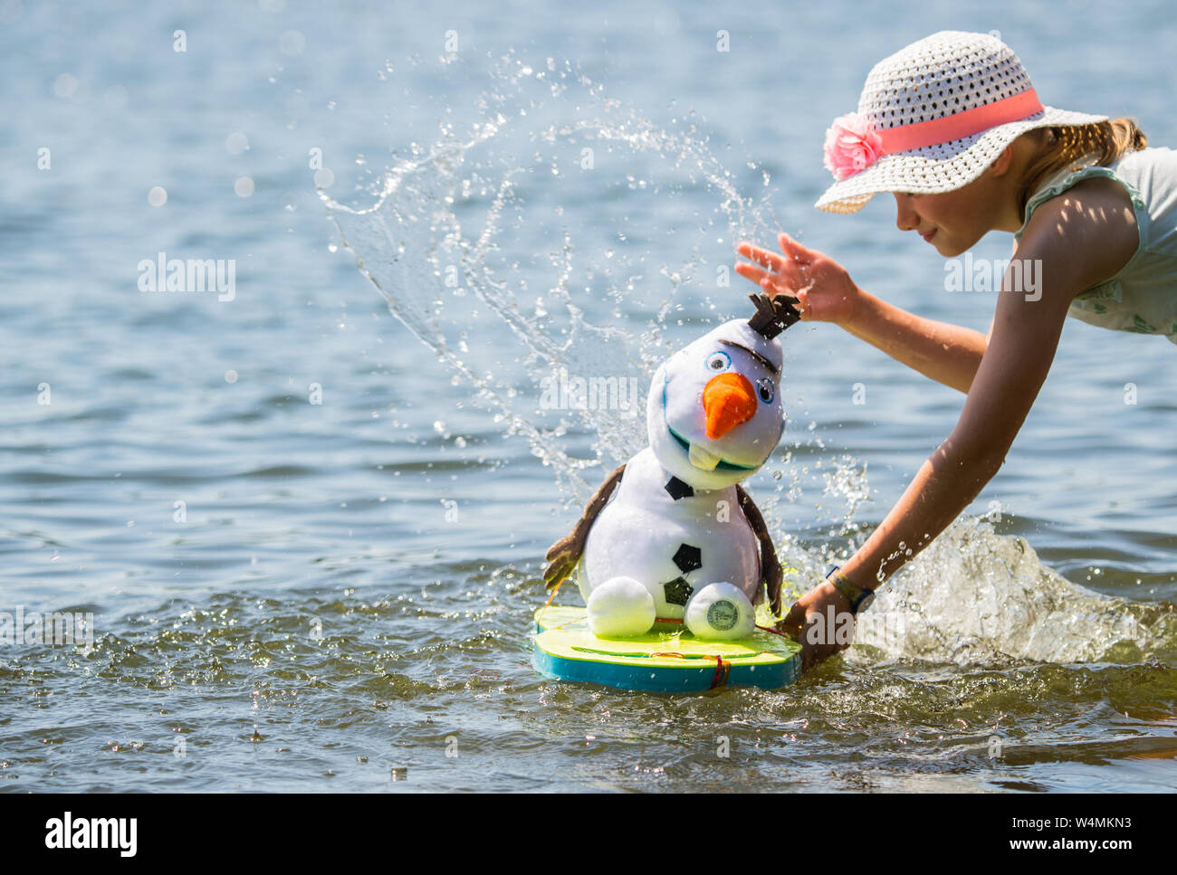 24 luglio 2019, Assia, Flörsheim: La ragazza Lilith aggiorna il suo tessuto pupazzo di Olaf, la figura del film Disney " Snow Queen', in questa giornata calda con acqua dalla principale nei pressi di Flörsheim. Foto: Andreas Arnold/dpa Foto Stock