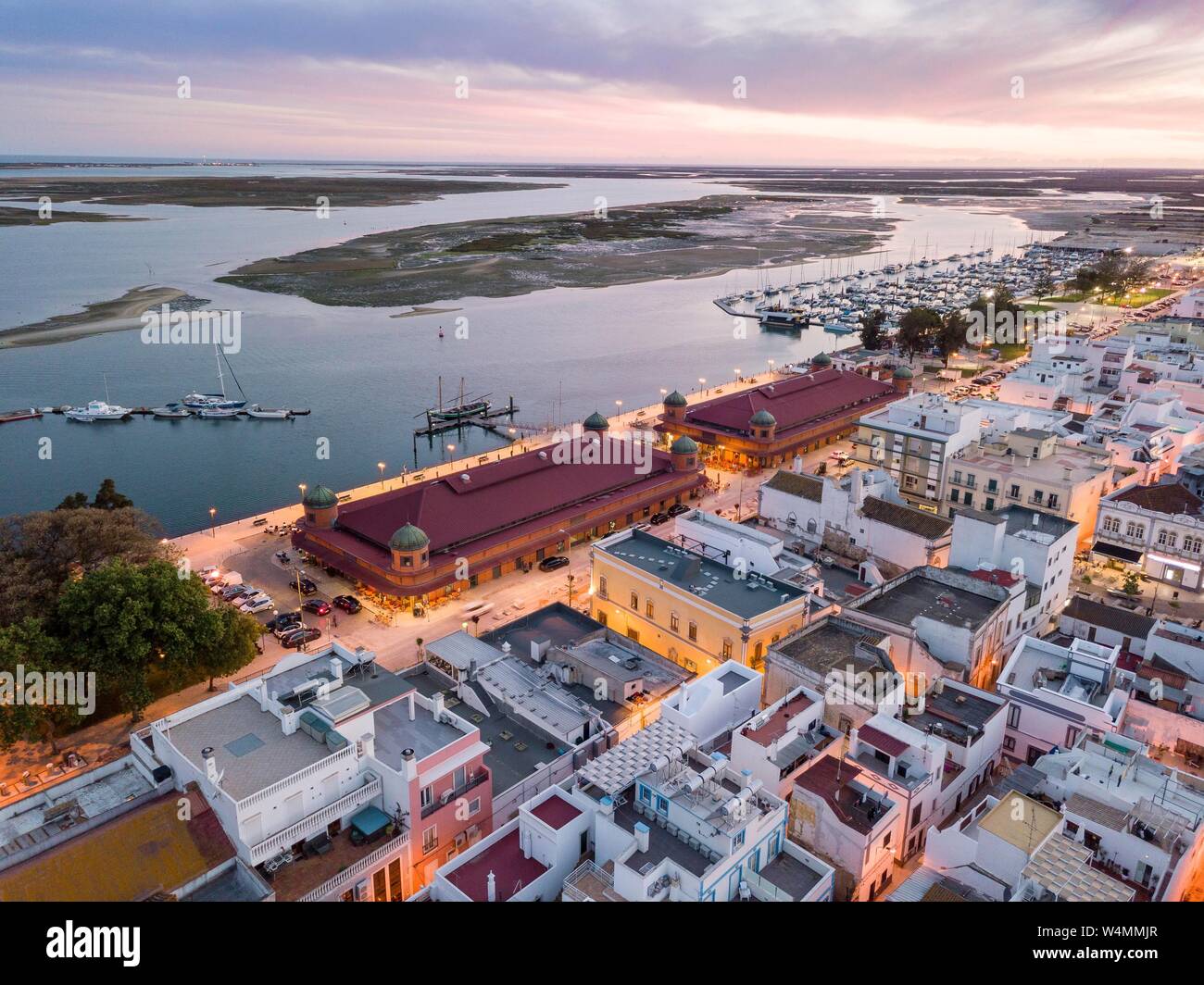 Vista città con due edifici di mercato e e il fiume Ria Formosa di sera, il Parco naturale di Ria Formosa, Olhao, Algarve, PORTOGALLO Foto Stock