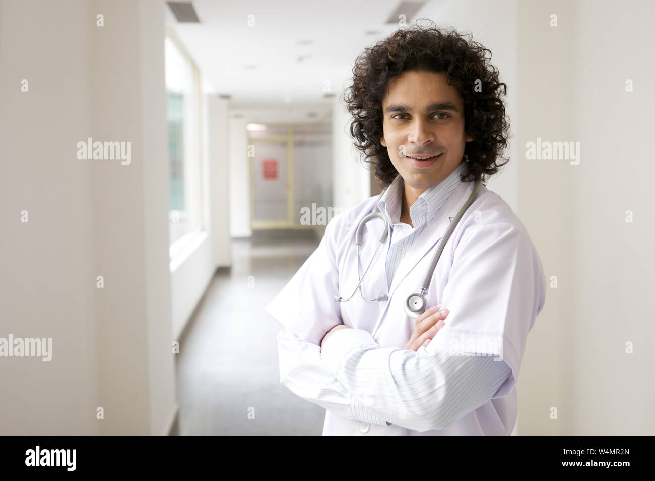 Medico maschio in piedi con le braccia incrociate Foto Stock