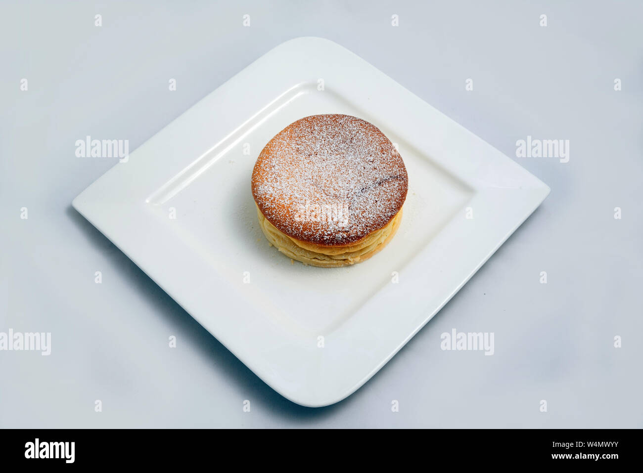 Un basso contrasto Hero Shot di una torta di pan su una piastra su un minimo di sfondo bianco con una diagonale di 60 gradi Foto Stock