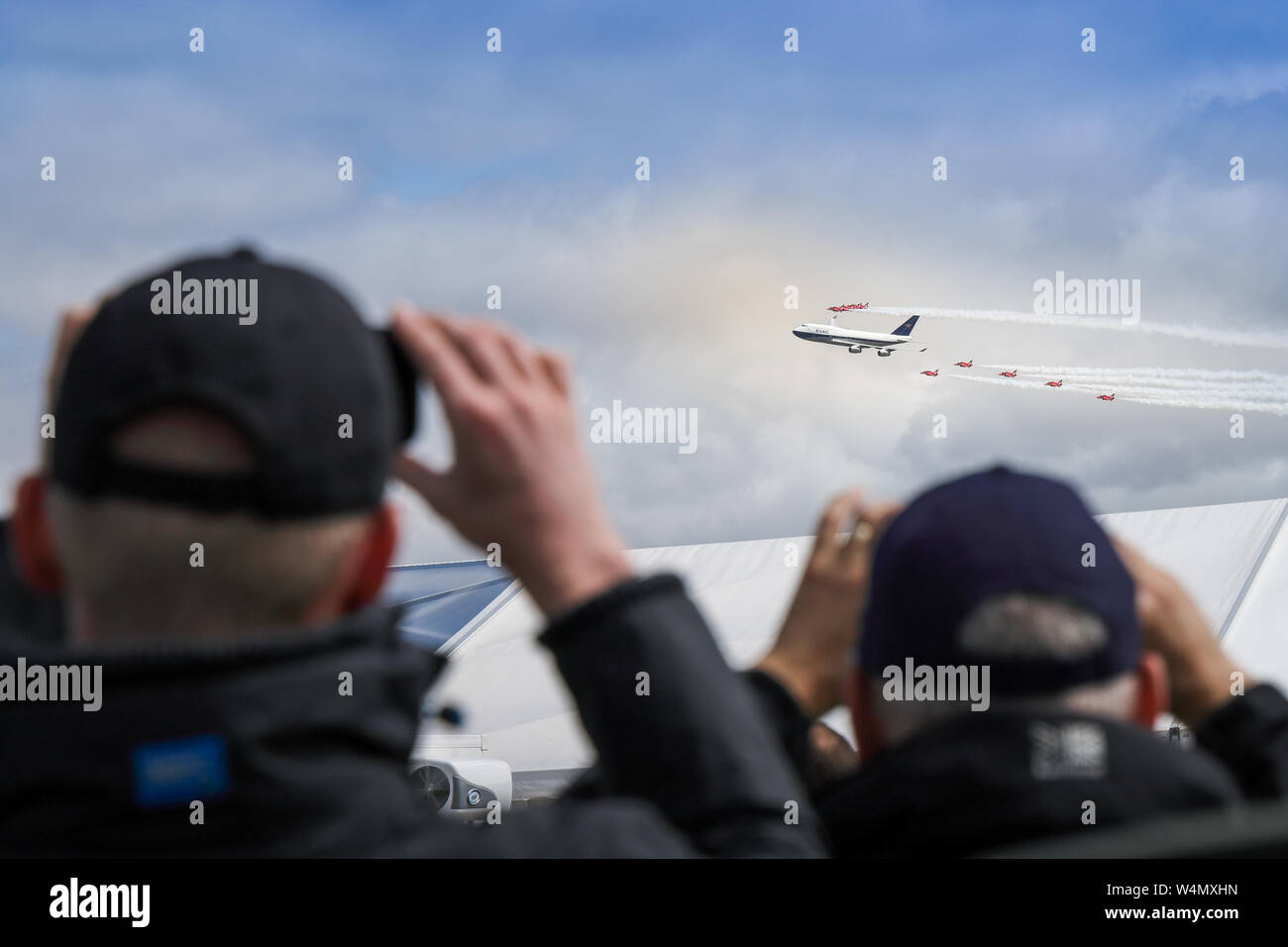 Aeromobile enthustiasts scattare fotografie con i loro telefoni cellulari di un display di volo da una livrea BOAC Boeing 747 400 in formazione con le frecce rosse Foto Stock