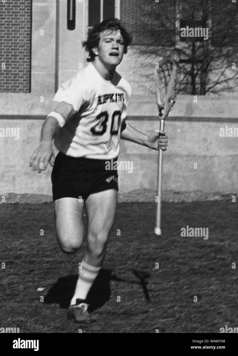 Johns Hopkins Lacrosse player Jack Thomas, in pantaloncini Hopkins e jersey, in esecuzione con il suo lacrosse stick nella sua mano sinistra sul campo, con un grave espressione facciale, 1977. Dalla storica collezione di fotografie. () Foto Stock