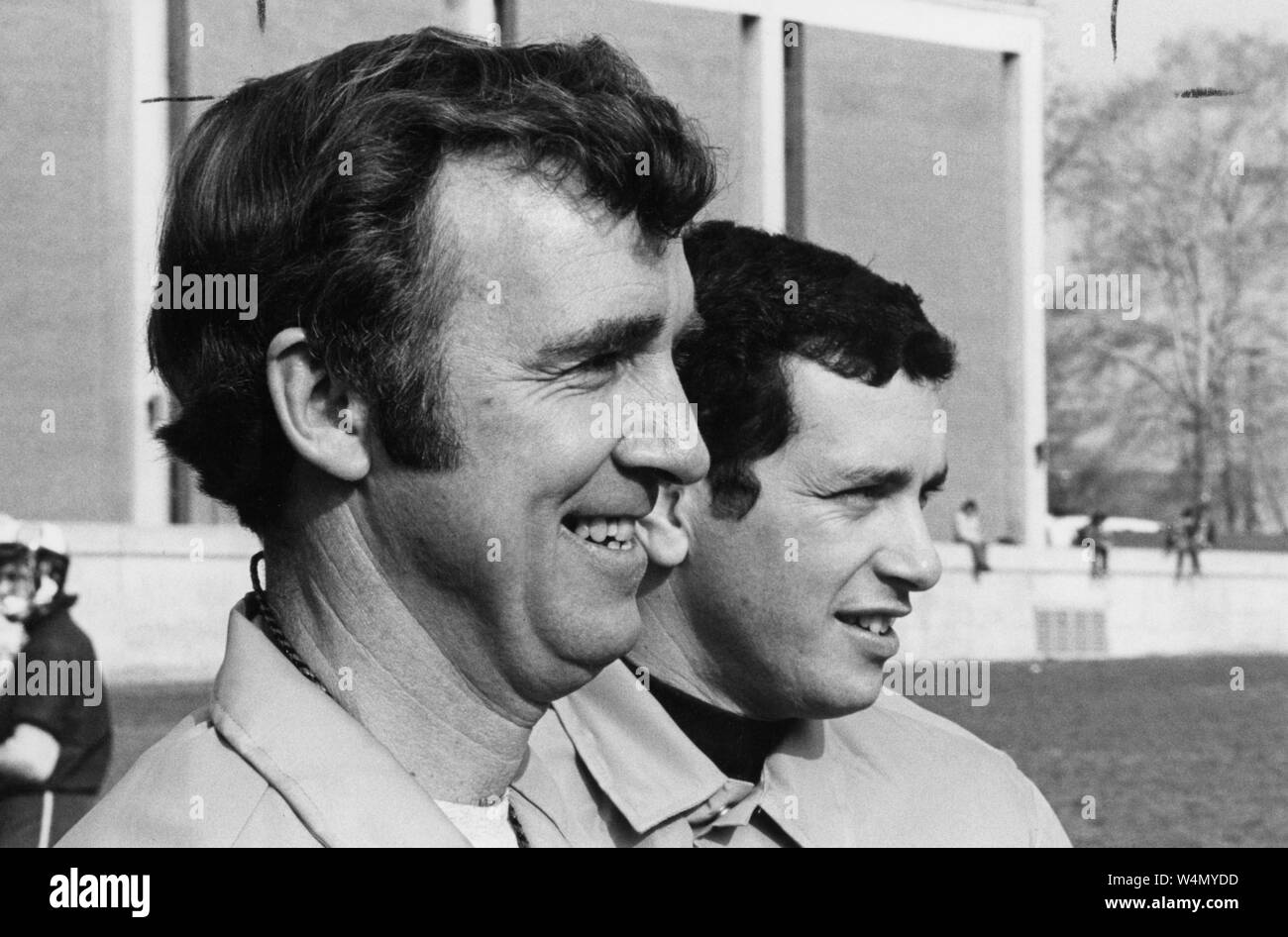 (Da sinistra a destra) un lato-angolo di close-up di Johns Hopkins lacrosse direttore, Bob Scott e lacrosse pullman, Henry Ciccarone, come hanno sorriso mentre si guarda il loro gioco di squadra, 1974. Dalla storica collezione di fotografie, Baltimore, Maryland. () Foto Stock