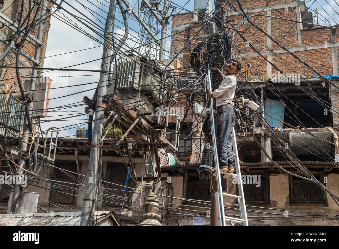 Tecnico su una scala Controllo di cavi in Kathmandu Foto Stock