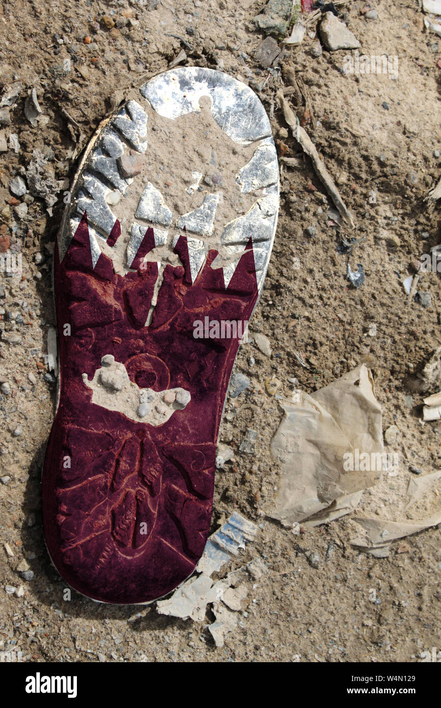 La bandiera del Qatar è raffigurato sulla suola di un vecchio boot. Concetto di ecologia con inquinamento ambientale da rifiuti domestici e industriali. Foto Stock