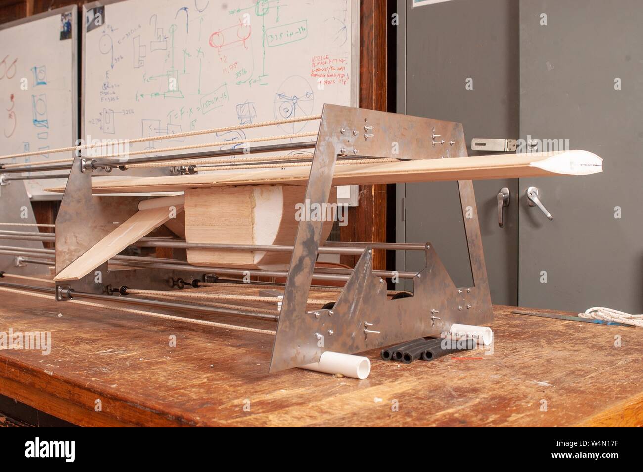 Un modello in legno di un'ala di aeroplano è tenuto in una apparecchiatura su un banco di lavoro in un contesto di laboratorio, con una lavagna contenenti formule matematiche in background, presso la Johns Hopkins University di Baltimore, Maryland, Aprile 30, 2004. Dall'Homewood raccolta di fotografie. () Foto Stock