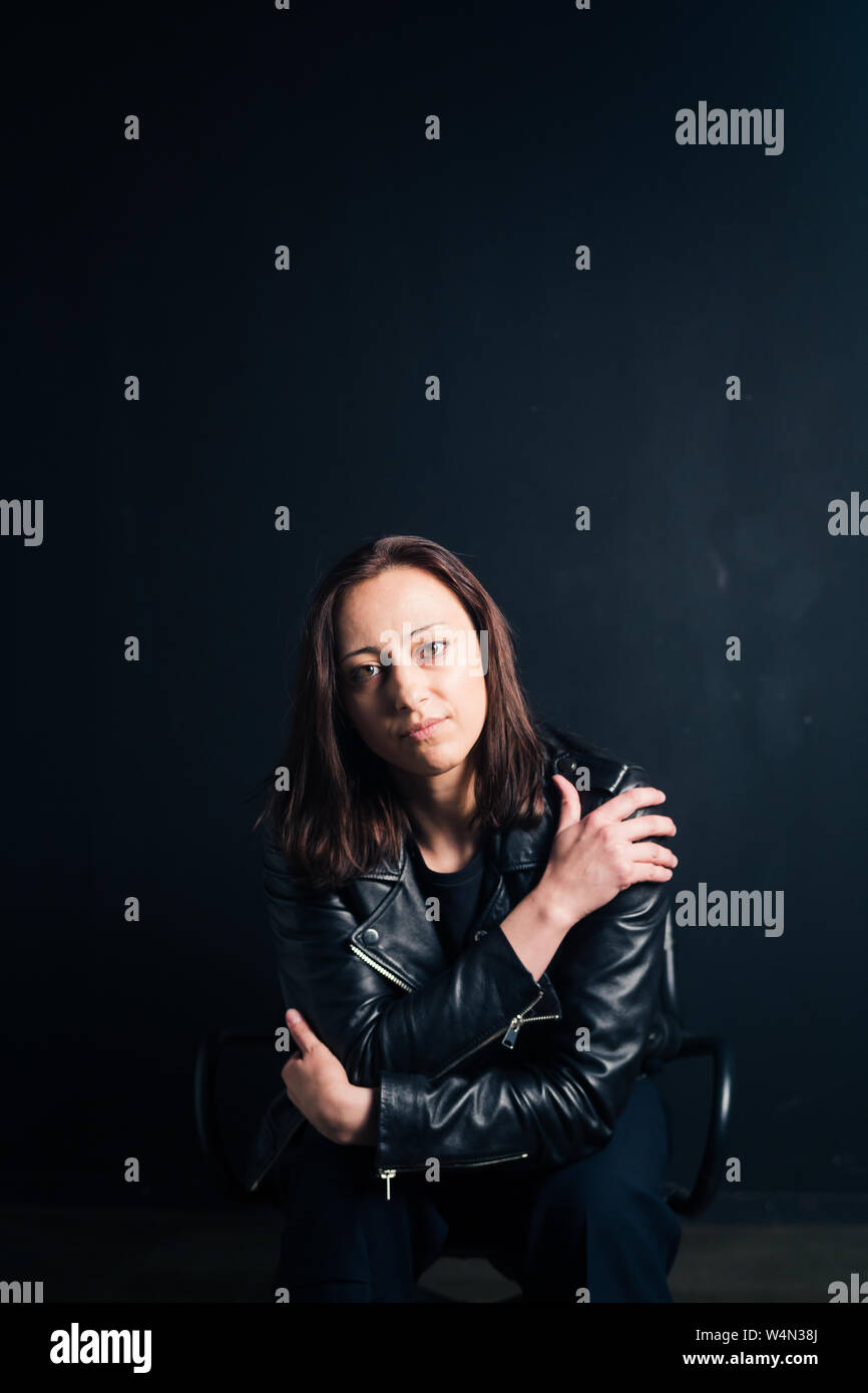 Ritratto in studio di un attraente giovane donna in un nero giacca di pelle contro uno sfondo semplice Foto Stock