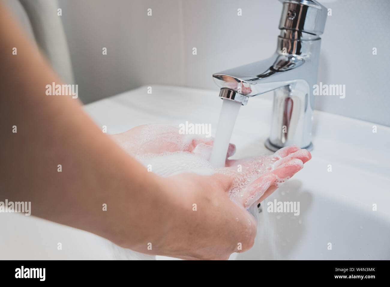 Lavarsi le mani con acqua in un lavandino. La pulizia delle mani, igiene personale concetto Foto Stock