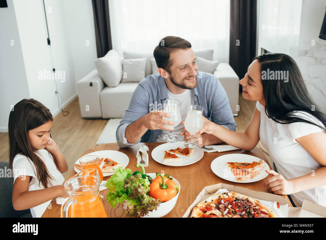 Famiglia, madre, padre e figlia durante la cena.Mangiare mangiare pizze a casa Foto Stock