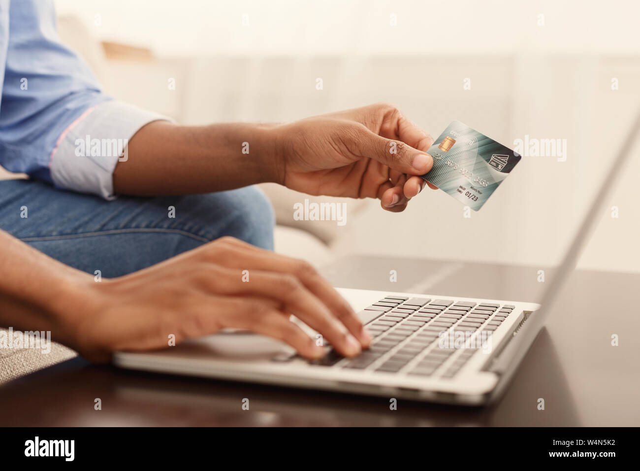 Uomo nero immettendo le informazioni sulla carta di credito tramite computer portatile Foto Stock